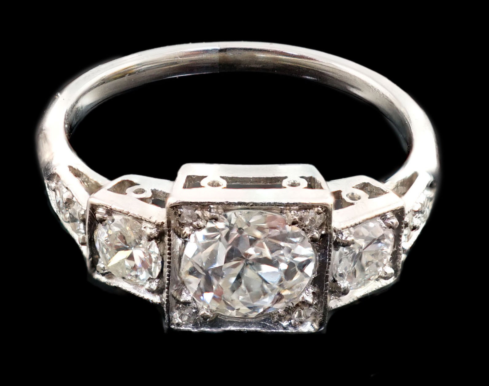 A platinum and millegrain set three stone diamond ring, with diamond set shoulders